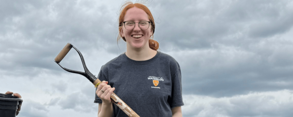 Alison Baird smiling and holding a shovel.