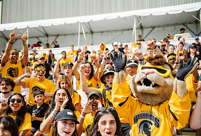 Waterloo students posing cheerfully with the Warrior mascot
